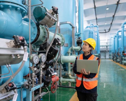 A female engineer works in a chemical plant using a laptop computer